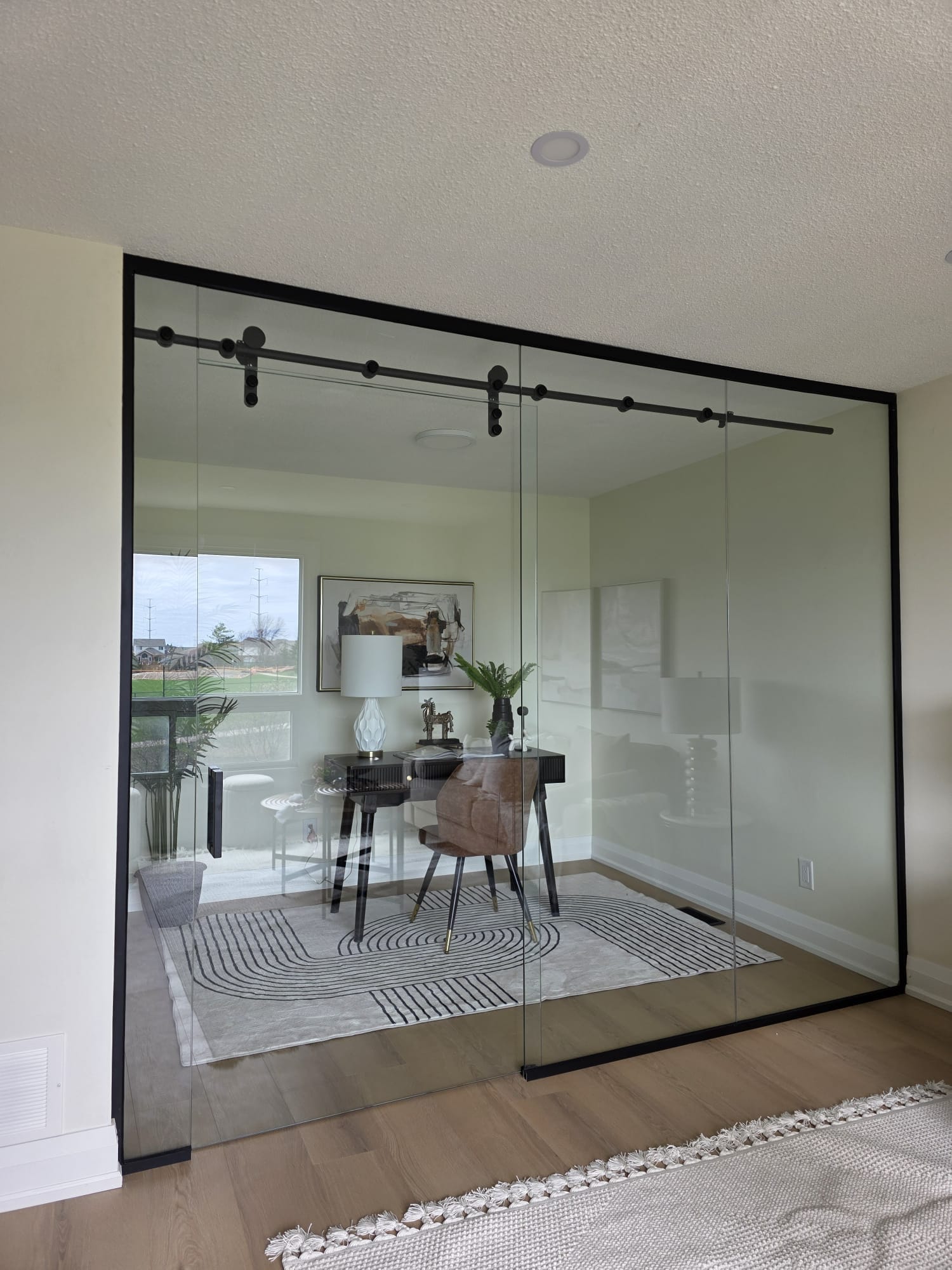 Black-frame glass home office enclosure with sliding barn-door style top track and panoramic window view — Built By Glass, GTA