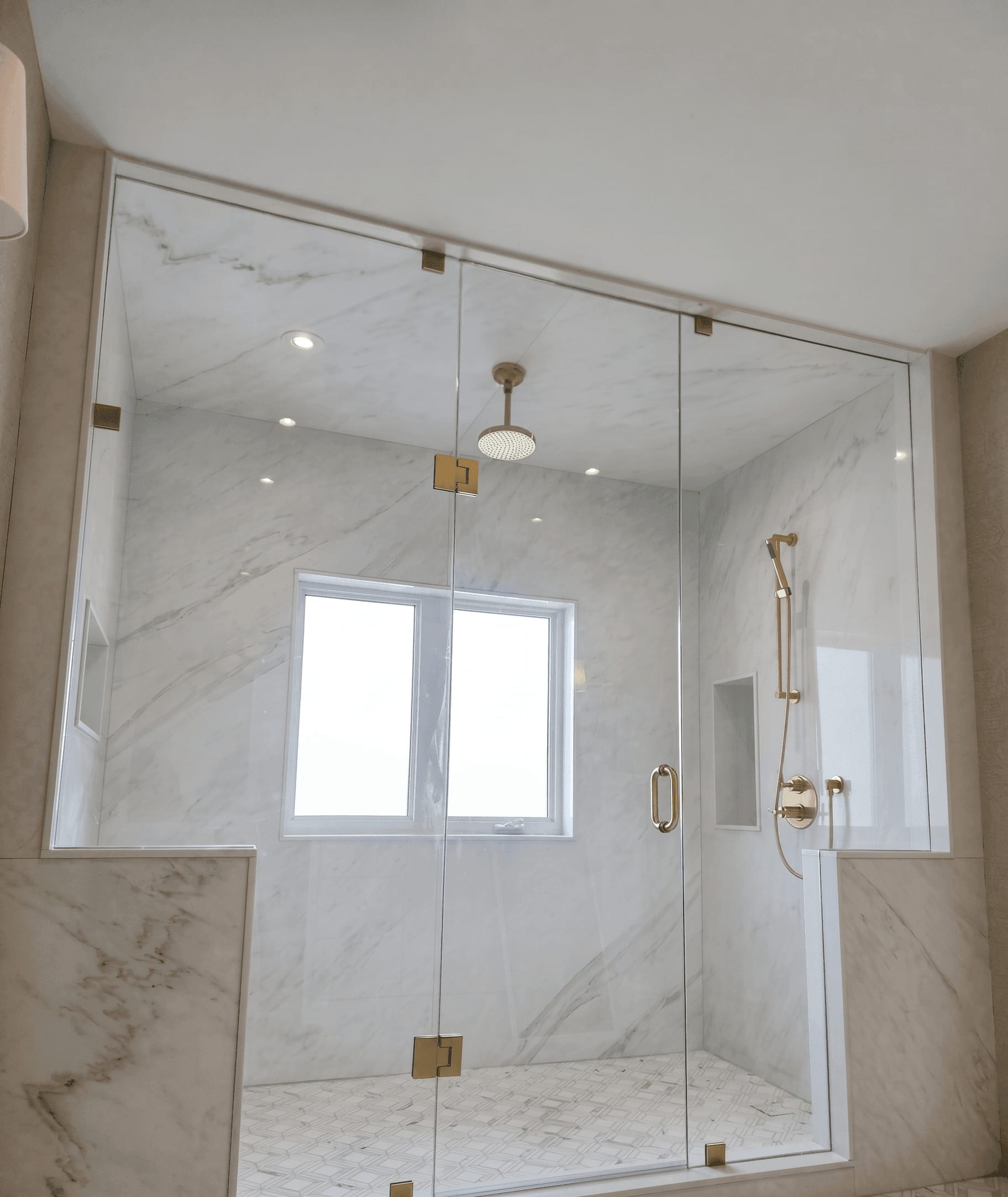 Custom frameless glass shower with satin brass hardware and Carrara marble tile — Built By Glass, Vaughan