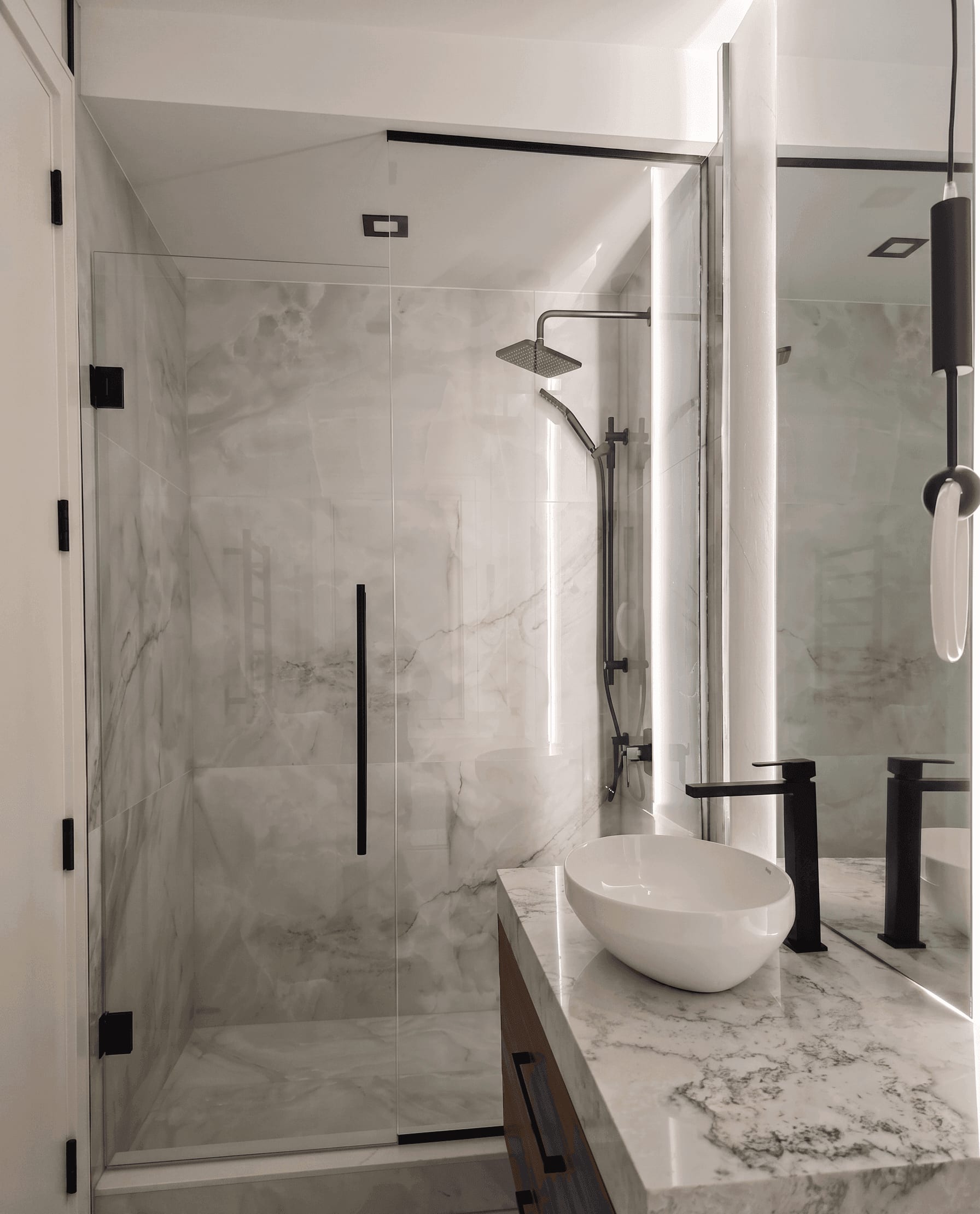 Frameless glass shower with matte black hardware and marble tile — Built By Glass