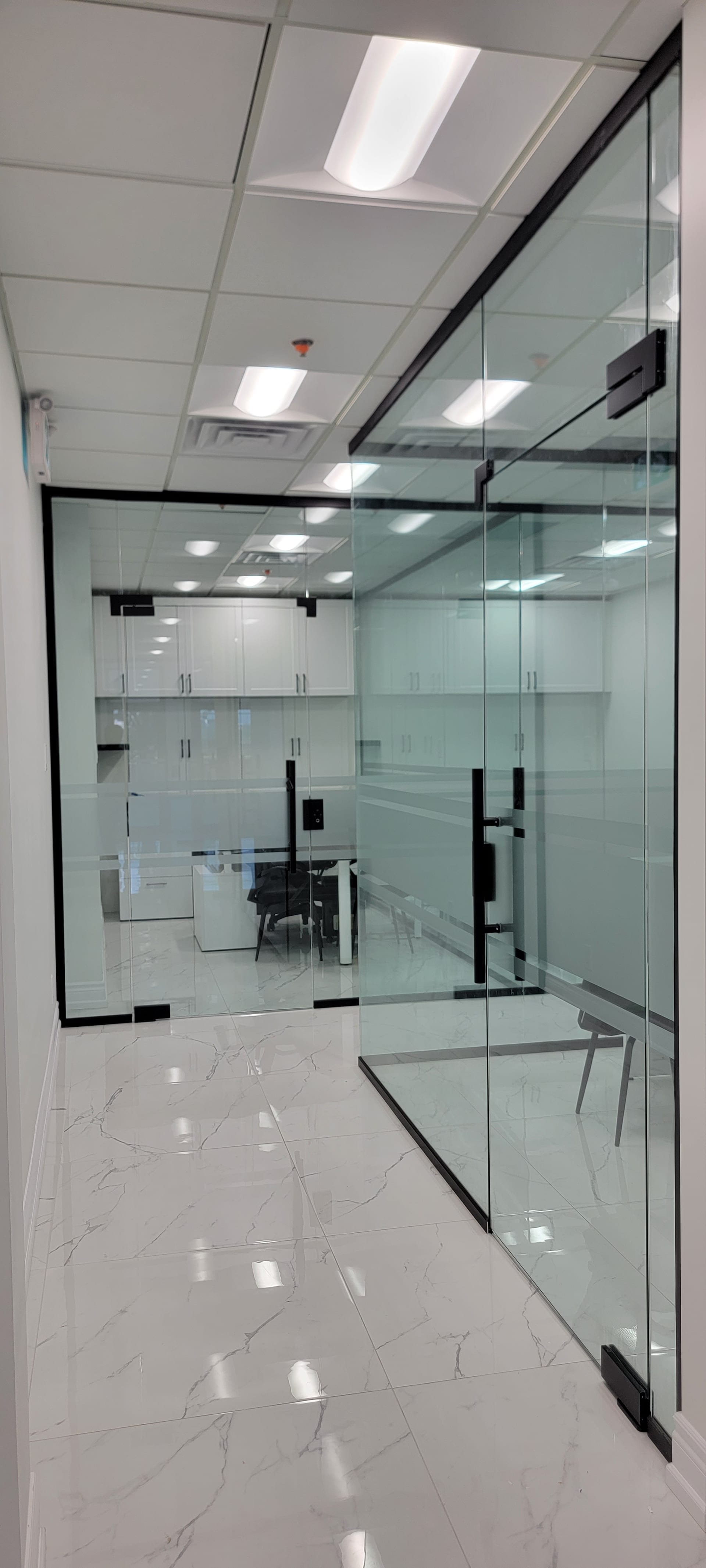 Floor-to-ceiling commercial glass office partition with matte black frame