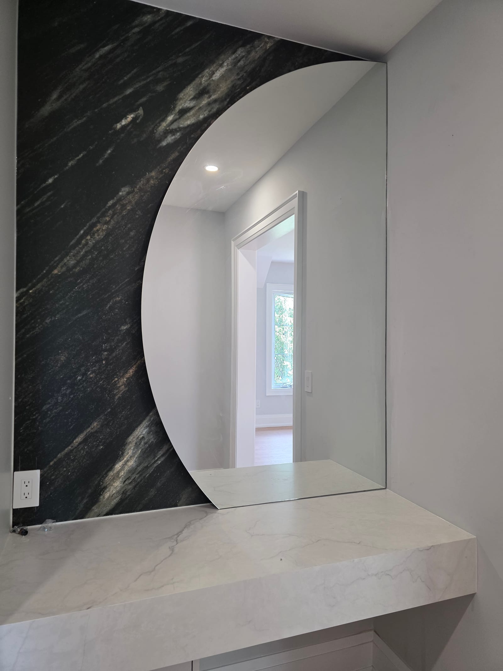 Round vanity mirror on a marble feature wall — Built By Glass